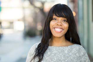 Woman with long dark hair standing on city street, blurry background